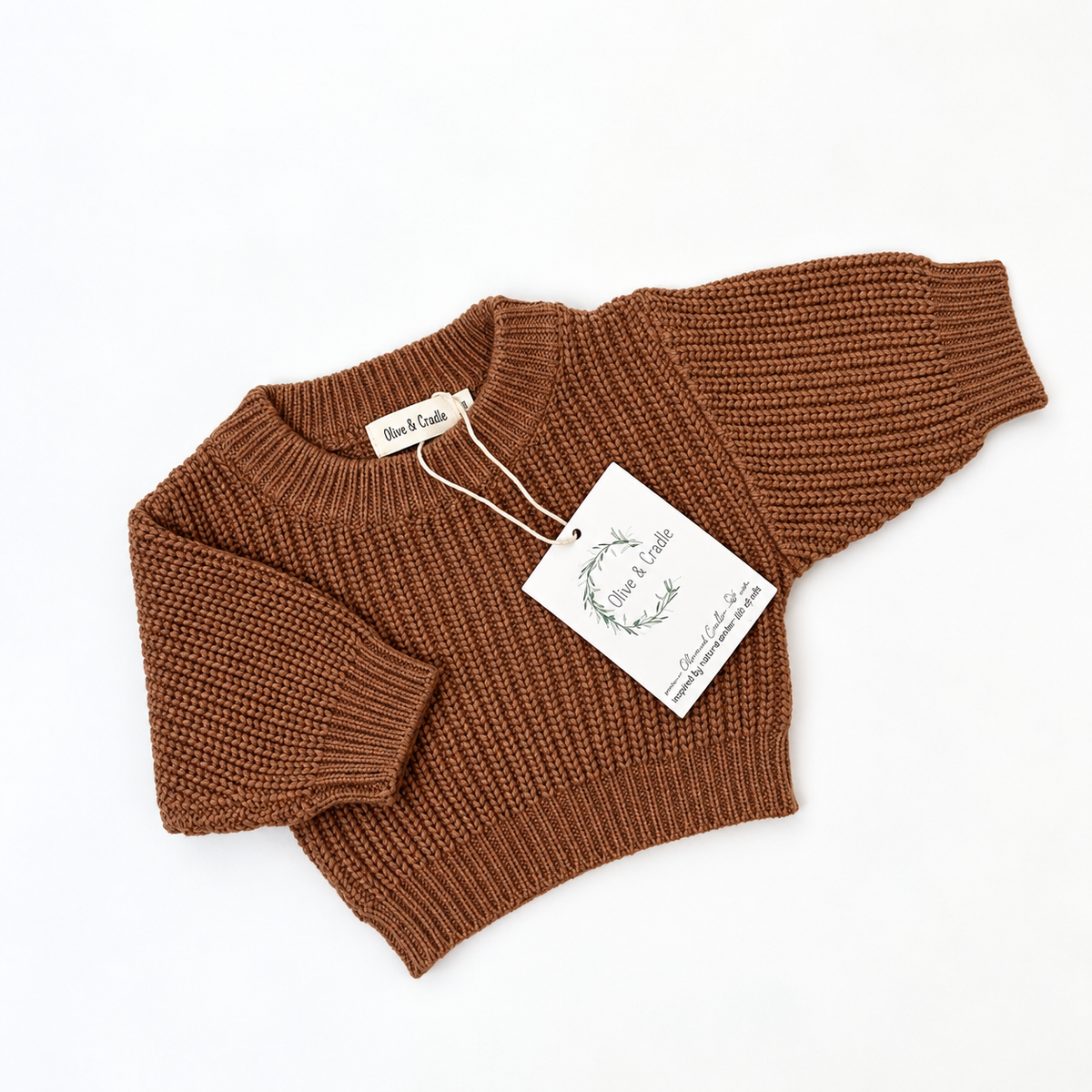 cinnamon ribbed knit sweater laid flat on a white background with a paper brand tag attached.
